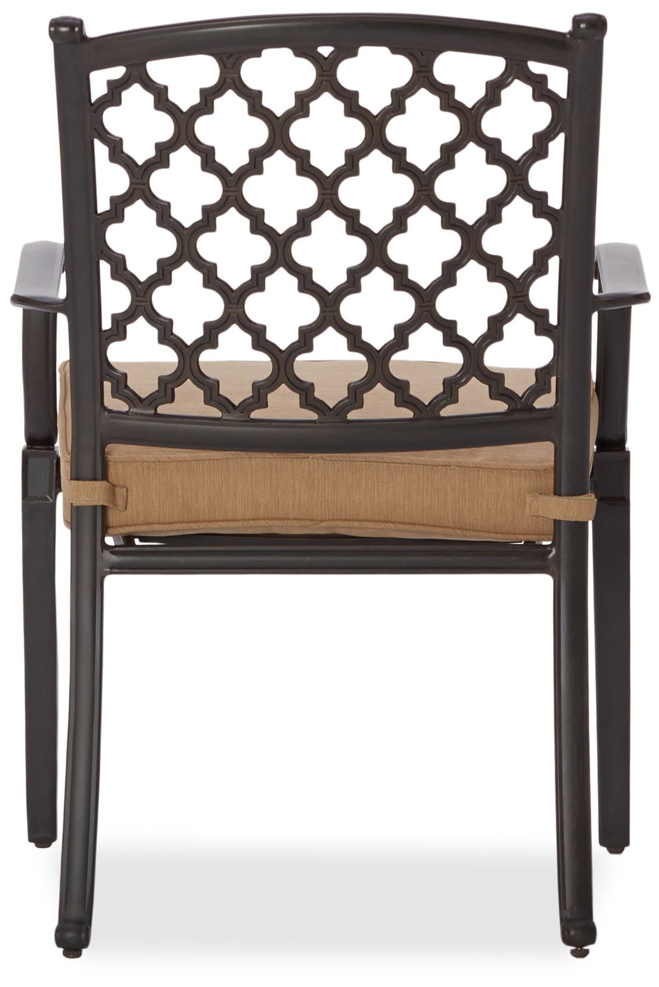 Front view of a Strathwood Whidbey dining arm chair with its tan cushion and decorative lattice back.