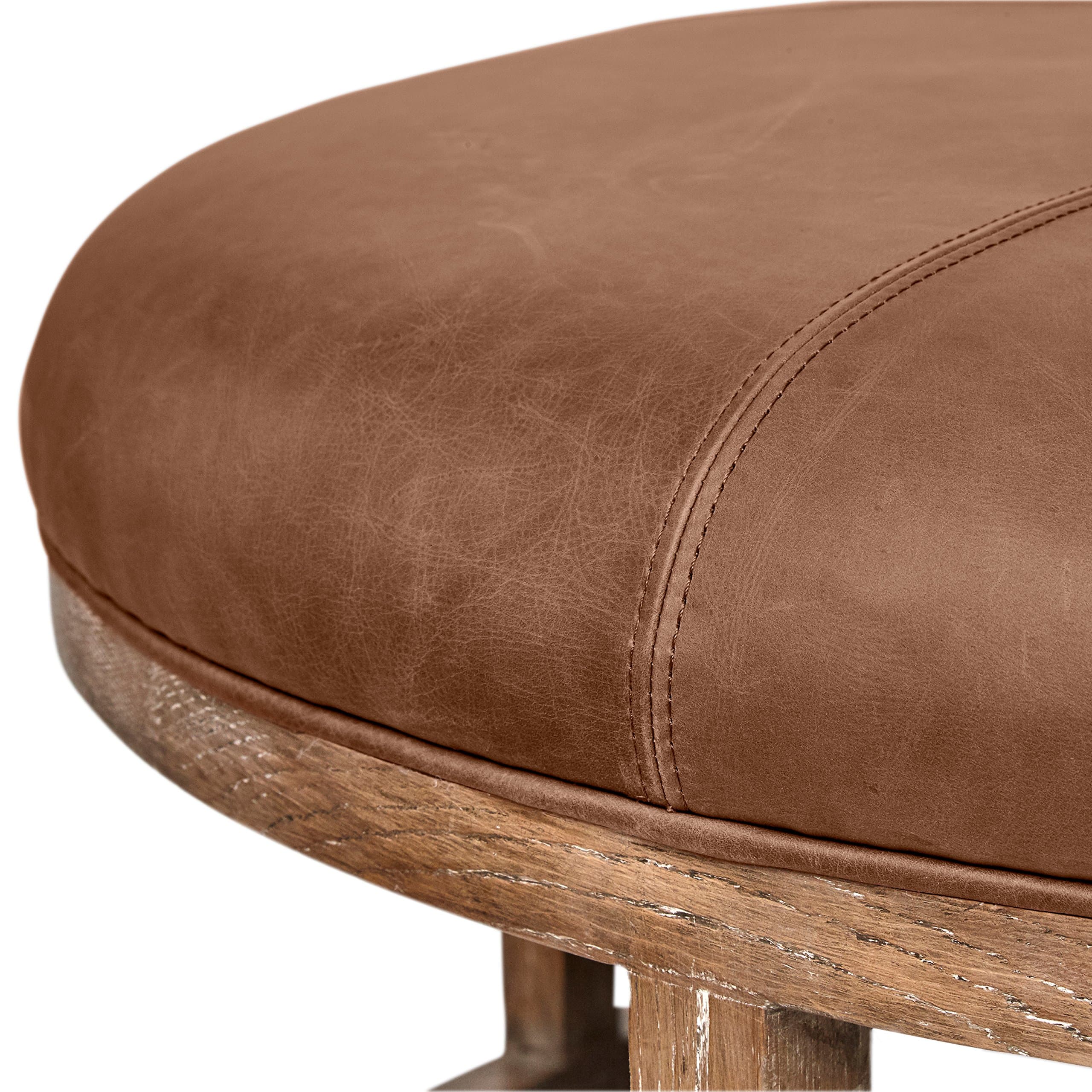Close view of the Norah ottoman leather edge, stitching and wood frame.